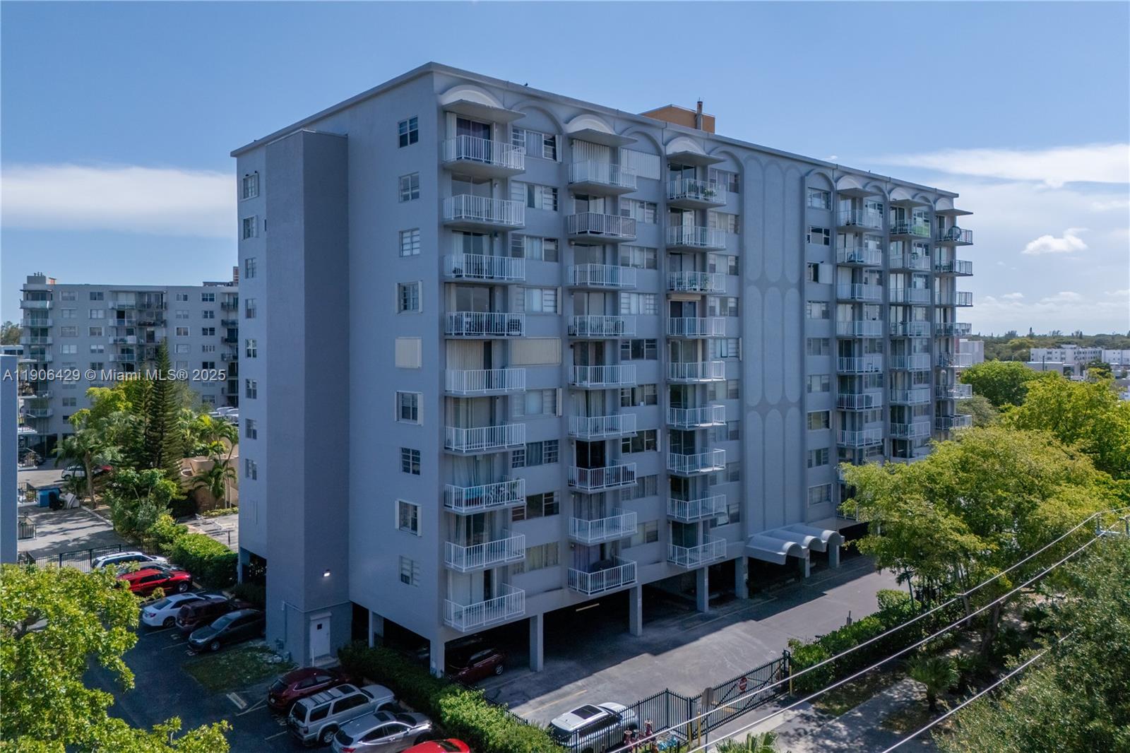 An aerial view of a multi-story residential apartment building with balconies and a parking lot — 1470 NE 125th Ter, North Miami FL 33161, NORTH MIAMI, FL