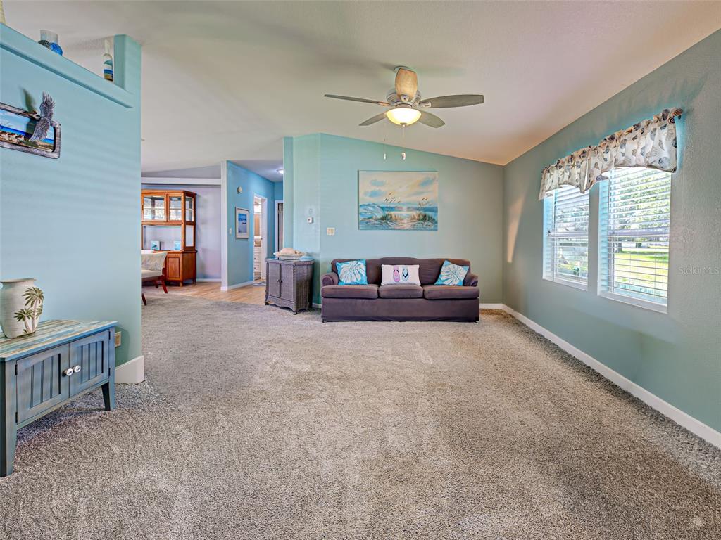 A living room features teal walls, a ceiling fan, wicker furniture, and a patterned rug — 6562 HIKINA DRIVE, NORTH PORT, FL