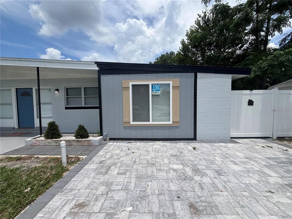 The exterior of a house features a gray-painted facade, a paved driveway, and a white fence — 6035 SAGE DRIVE, ORLANDO, FL
