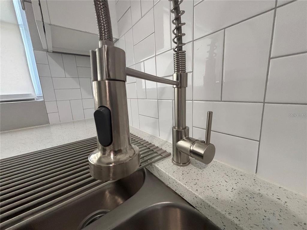 A stainless steel pull-down kitchen faucet is mounted on a white speckled countertop — 6035 SAGE DRIVE, ORLANDO, FL