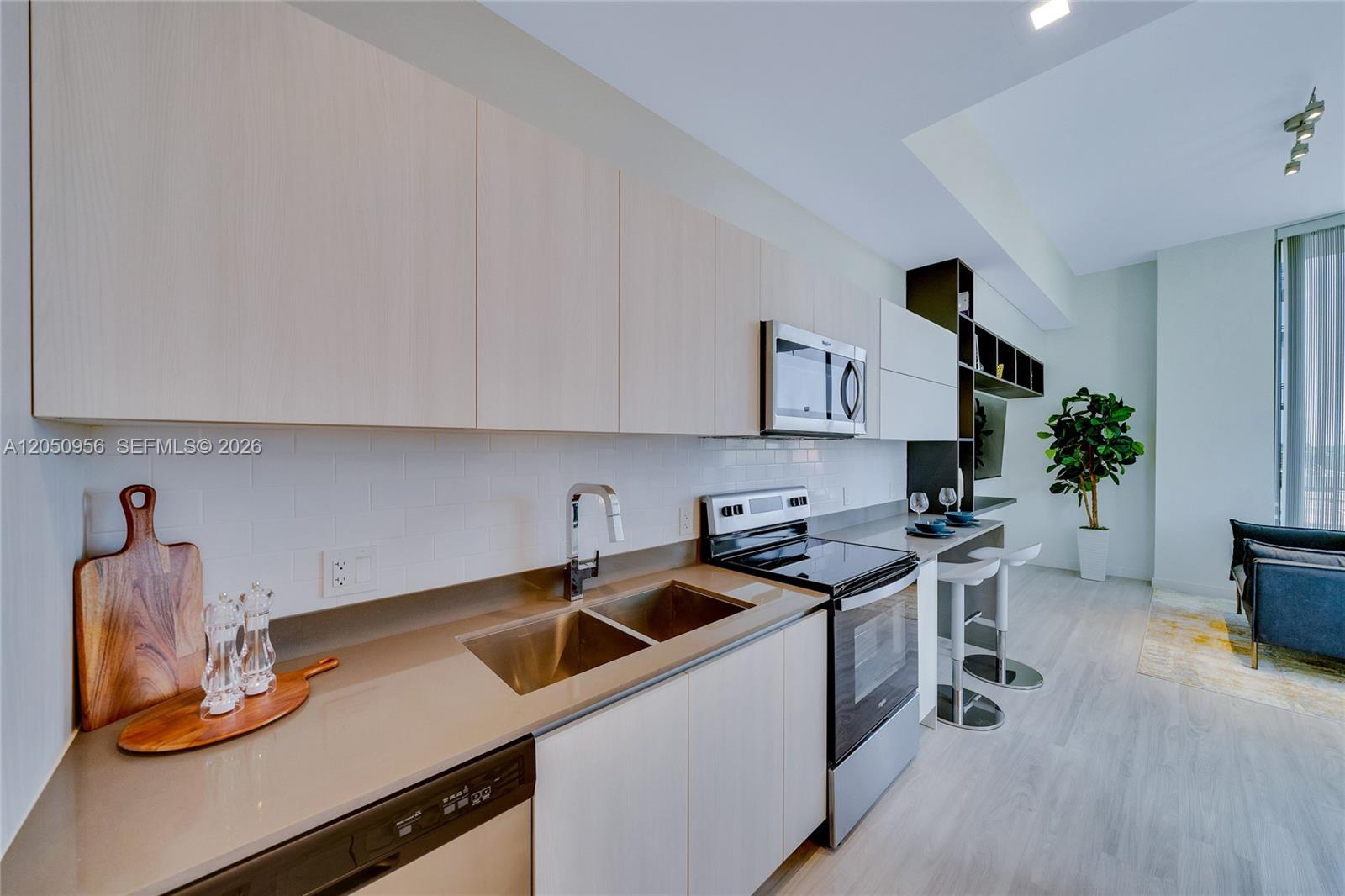 A modern kitchen features light wood cabinets, stainless steel appliances, and a breakfast bar — 1809 Jackson St, Hollywood FL 33020, HOLLYWOOD, FL
