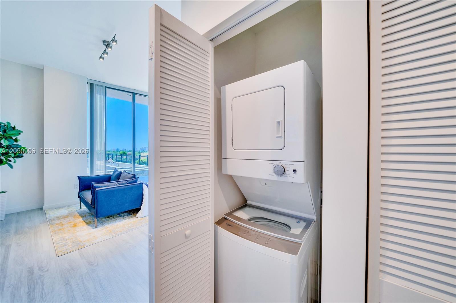 A stacked washer and dryer unit sits inside a closet next to a living area — 1809 Jackson St, Hollywood FL 33020, HOLLYWOOD, FL