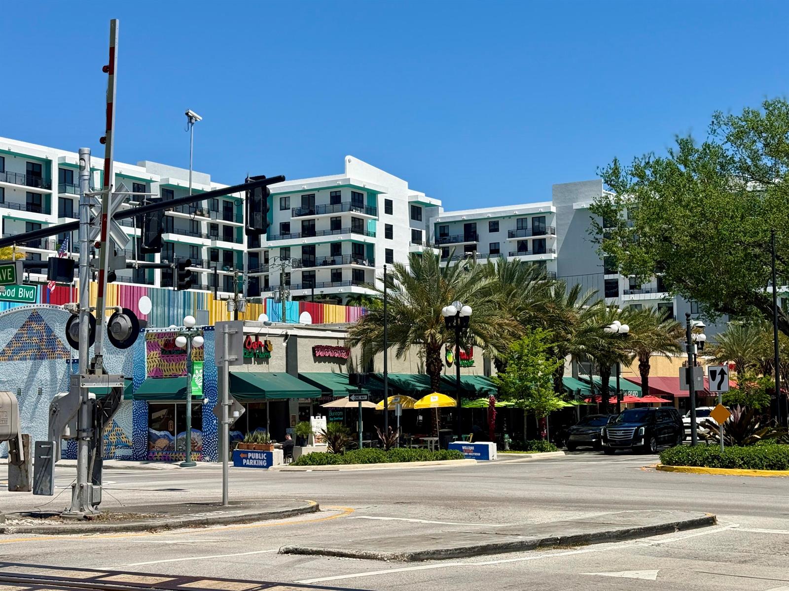 A street-level view shows a multi-story apartment building behind a row of colorful storefronts — 140 S Dixie Highway # 1002, Hollywood FL 33020, HOLLYWOOD, FL