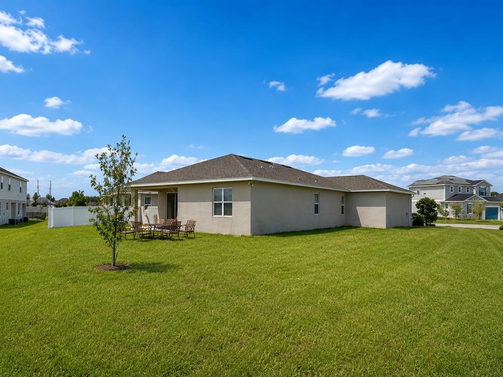 The exterior rear view of a beige single-story house with a large grassy backyard — 236 HILLCREST DRIVE, DUNDEE, FL