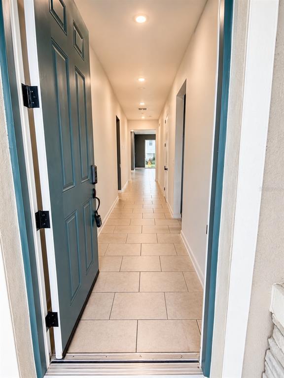 A teal front door opens into a long hallway with light-colored tile flooring — 236 HILLCREST DRIVE, DUNDEE, FL
