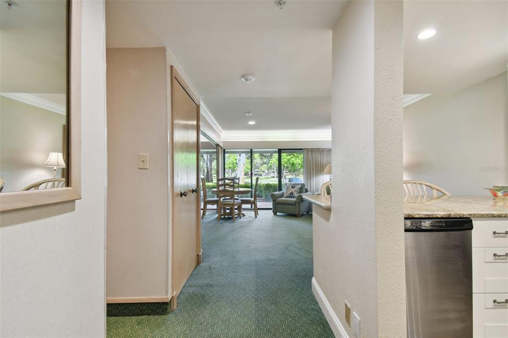 A view from a kitchen hallway looking toward a dining area and living room — 36750 US HIGHWAY 19 UNIT 23-110, PALM HARBOR, FL