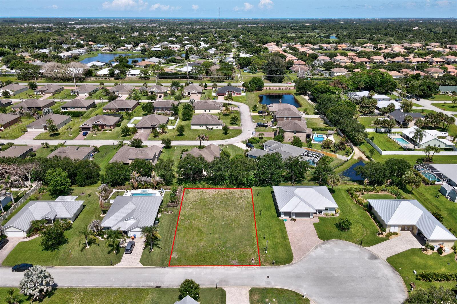 An aerial view shows a vacant residential lot outlined in red between two houses — 6370 Tropical Way, Vero Beach FL 32967, VERO BEACH, FL