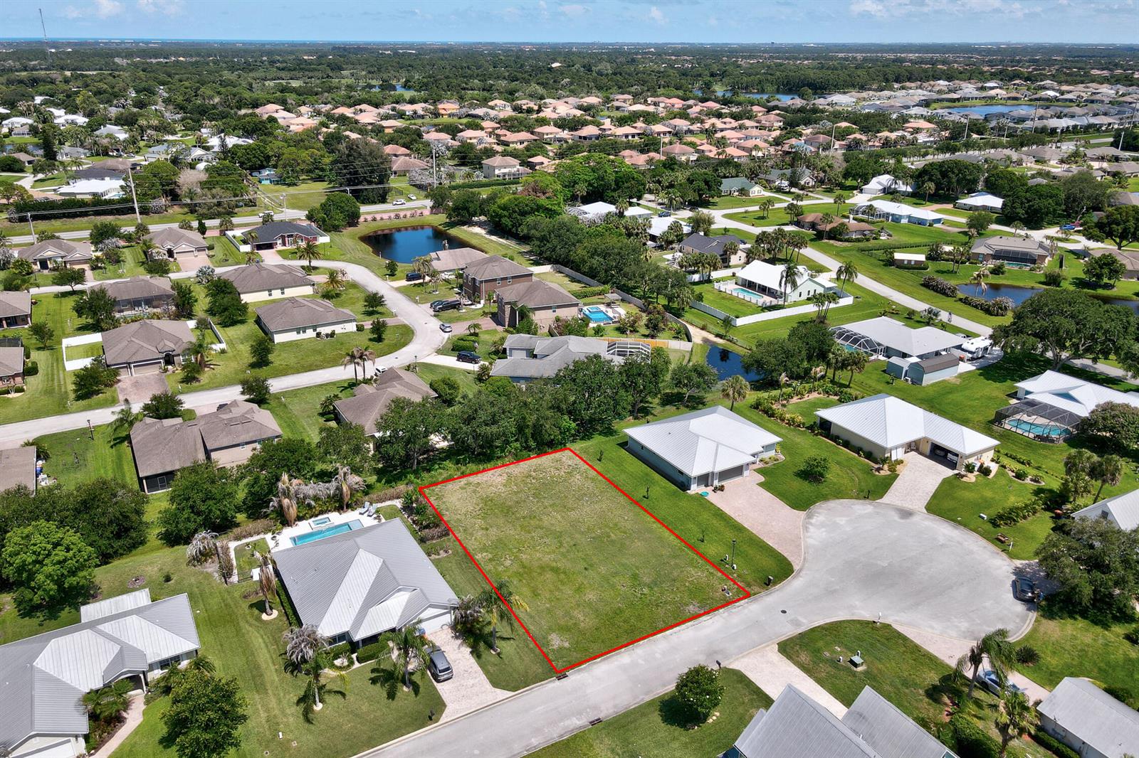 An aerial view shows a vacant, rectangular residential lot outlined in red within a suburban neighborhood — 6370 Tropical Way, Vero Beach FL 32967, VERO BEACH, FL