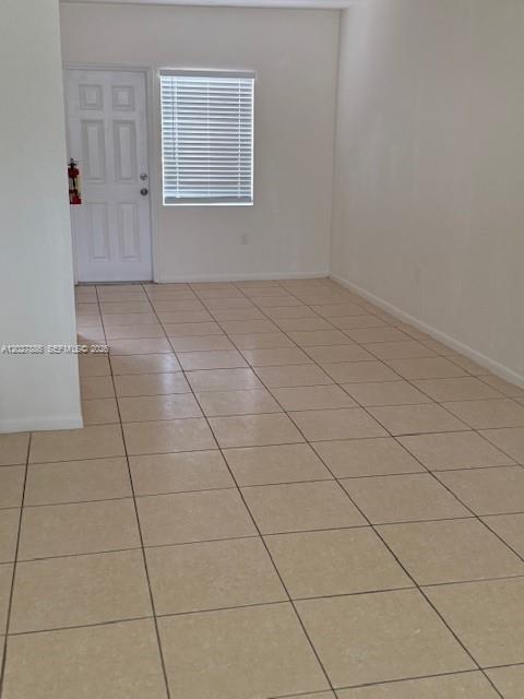 An empty room features light-colored tile flooring, white walls, and a single white door — 215 NW 84th St # 215, Miami FL 33150, MIAMI, FL