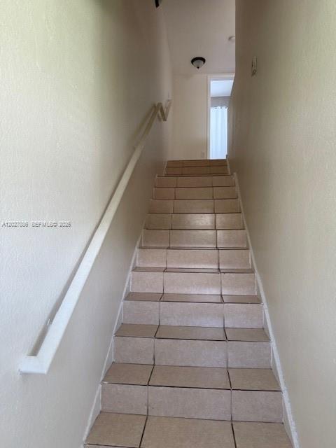 A staircase with beige tiled steps and a white handrail leads to an upper landing — 215 NW 84th St # 215, Miami FL 33150, MIAMI, FL