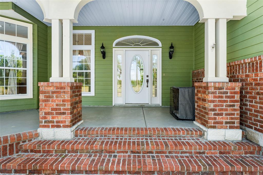 A front porch with brick steps, white columns, and a white front door with sidelights — 20952 60TH TERRACE, LIVE OAK, FL
