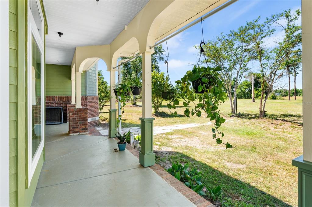 A covered porch with green columns, hanging plants, and a view of a grassy yard — 20952 60TH TERRACE, LIVE OAK, FL