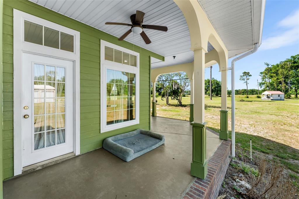 A covered porch with green siding, a ceiling fan, and a dog bed on concrete — 20952 60TH TERRACE, LIVE OAK, FL