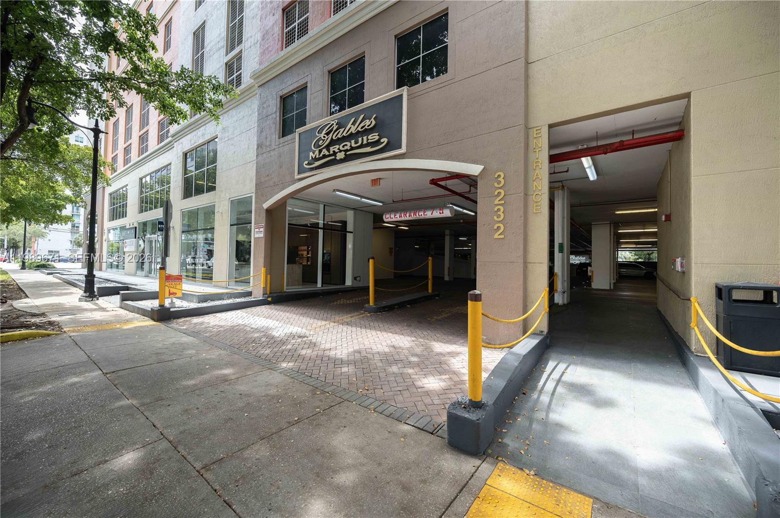 The exterior of a parking garage entrance features a brick driveway and yellow safety bollards — 3232 SW Coral Way # 1504, Miami FL 33145, MIAMI, FL