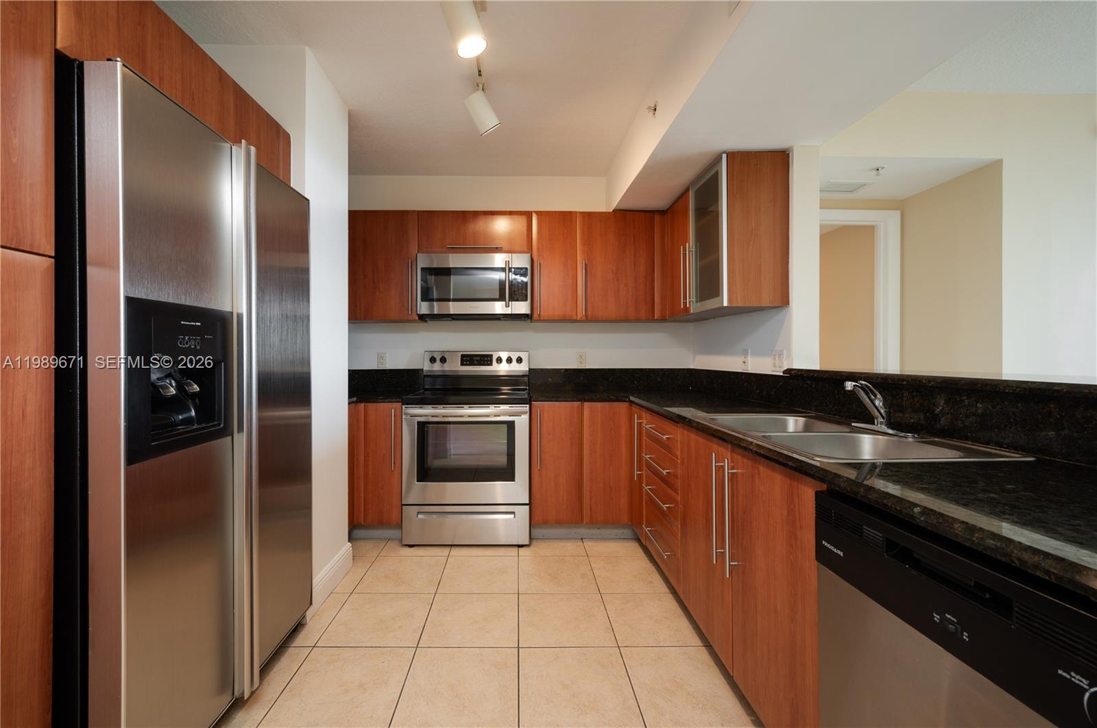 A kitchen features wood cabinets, stainless steel appliances, dark granite countertops, and light tile flooring — 3232 SW Coral Way # 1504, Miami FL 33145, MIAMI, FL