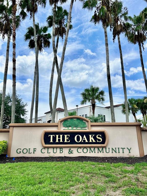 A sign for The Oaks Golf Club & Community stands before palm trees and buildings — 2300 THE OAKS BOULEVARD, KISSIMMEE, FL