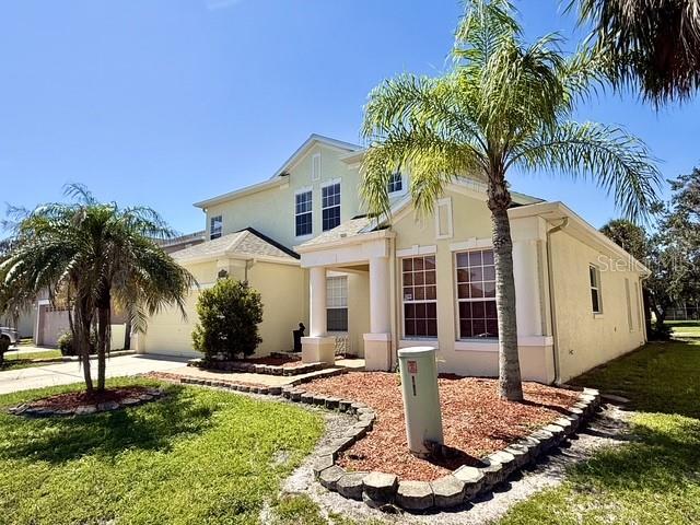 A two-story, light-yellow house with a palm tree in the front yard — 2300 THE OAKS BOULEVARD, KISSIMMEE, FL