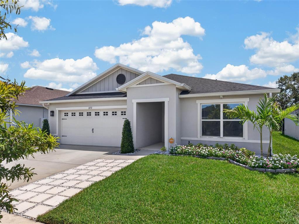 A single-story house with a light gray exterior, a two-car garage, and a landscaped yard — 13737 RUSHING CREEK RUN, ORLANDO, FL