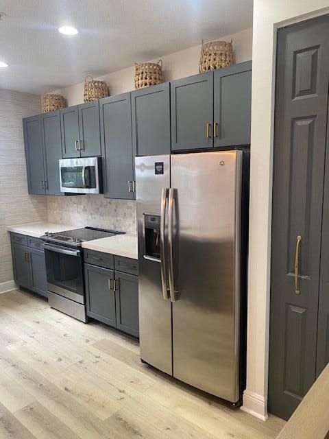A kitchen features dark gray cabinets, stainless steel appliances, and light wood-look flooring — 229 N Latitude Circle, Delray Beach FL 33483, DELRAY BEACH, FL