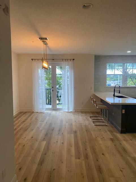 A dining area with wood floors, a pendant light, and glass doors leading to a balcony — 229 N Latitude Circle, Delray Beach FL 33483, DELRAY BEACH, FL
