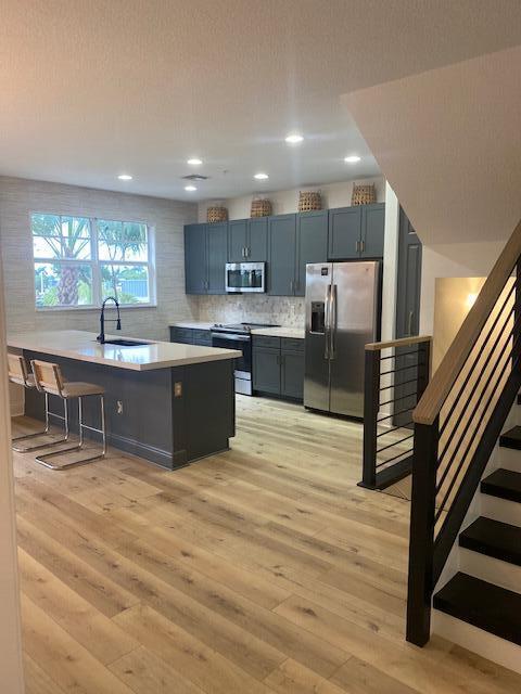 A kitchen with dark gray cabinets, a large island, and light wood flooring — 229 N Latitude Circle, Delray Beach FL 33483, DELRAY BEACH, FL