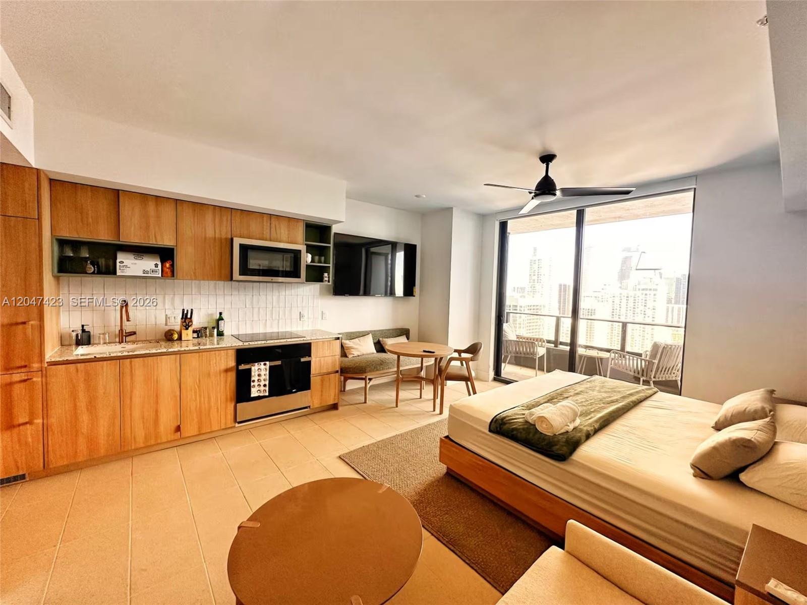 A studio apartment features a kitchen with wood cabinets, a bed, and a balcony view — 159 NE 6th St # 3212, Miami FL 33132, MIAMI, FL