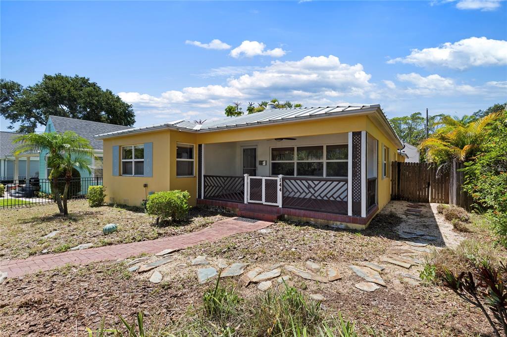 A yellow single-story house features a covered front porch with a decorative railing and walkway — 144 30TH AVENUE NE, ST PETERSBURG, FL