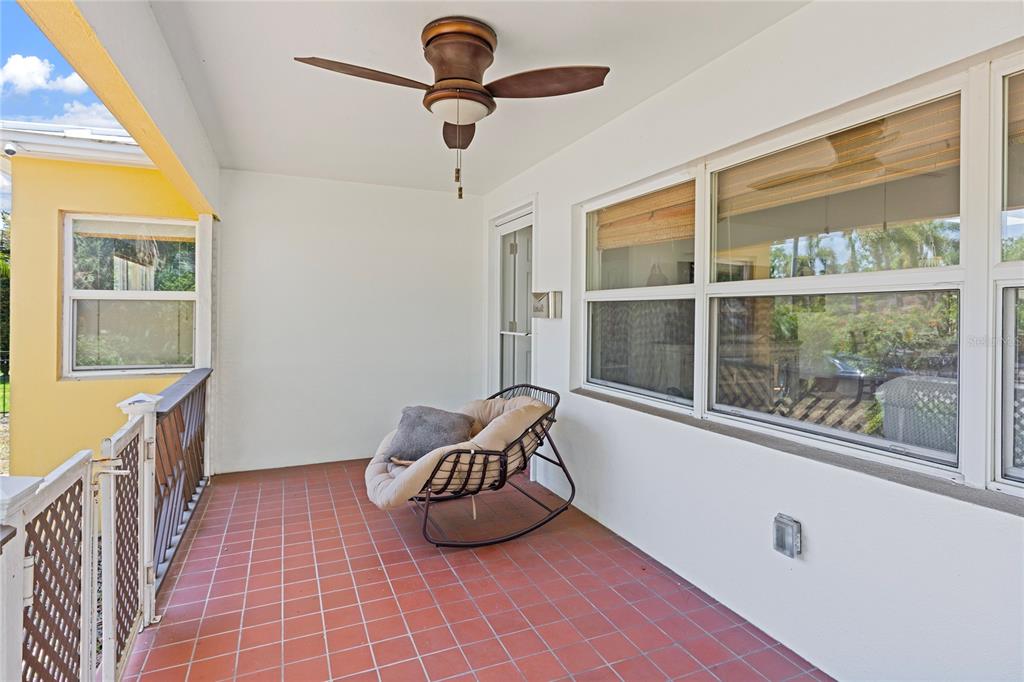 A covered patio features red tile flooring, a ceiling fan, and a round rocking chair — 144 30TH AVENUE NE, ST PETERSBURG, FL