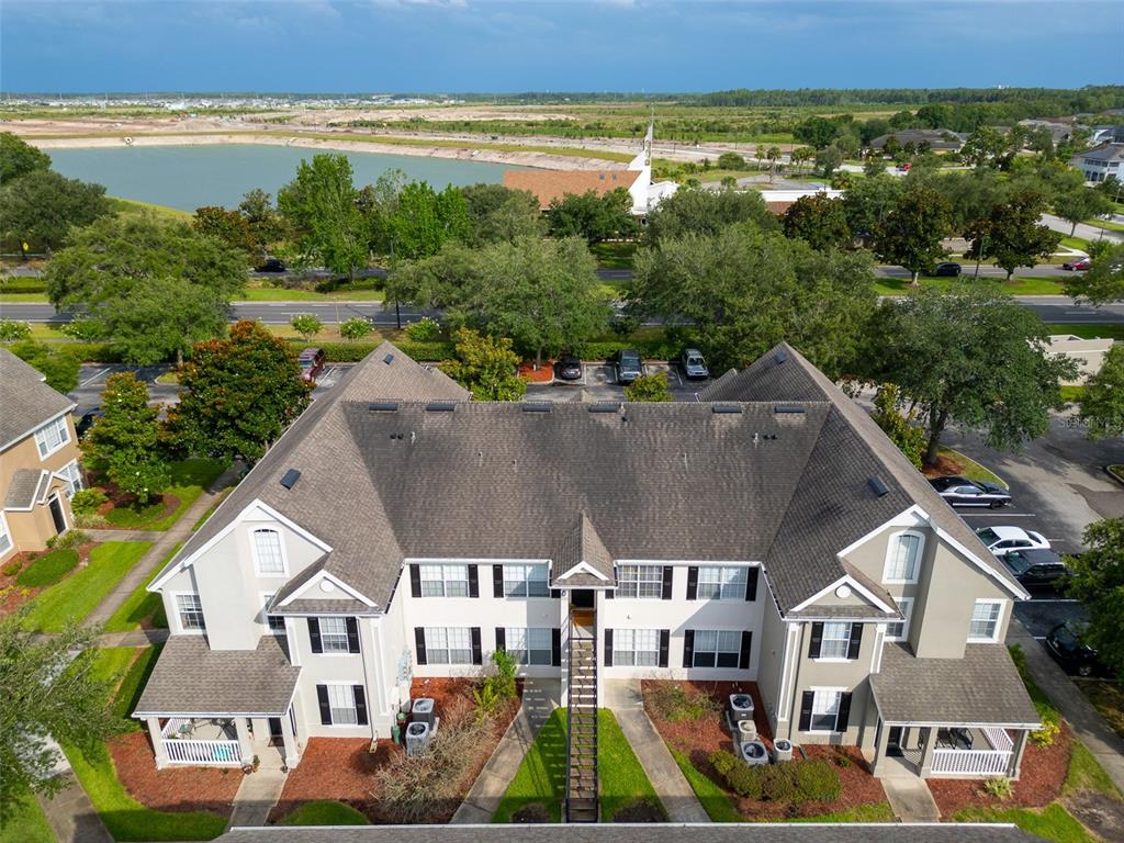 An aerial view of a multi-story apartment building with a shingled roof and parking lot — 8933 LEE VISTA BOULEVARD UNIT 2607, ORLANDO, FL