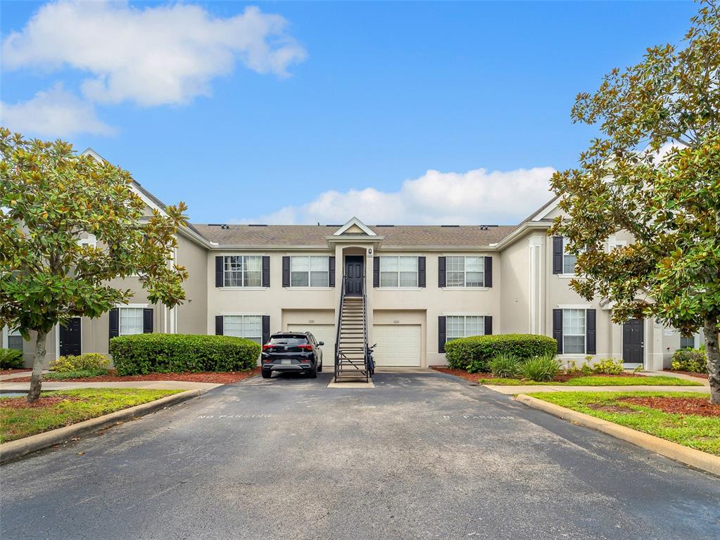 A two-story apartment building with a central staircase, two garages, and a parked car — 8933 LEE VISTA BOULEVARD UNIT 2607, ORLANDO, FL