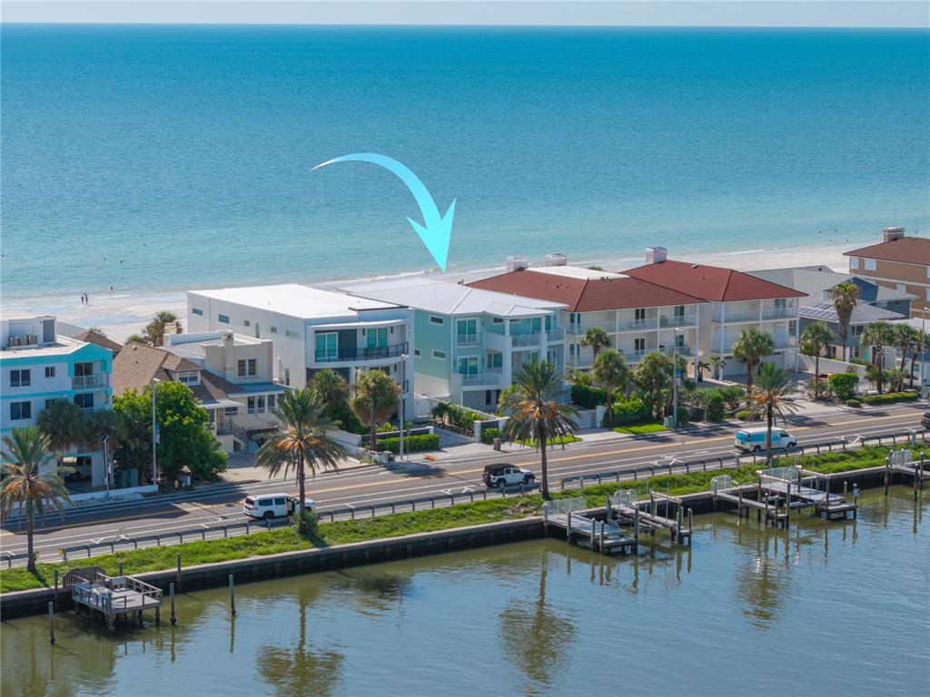 An aerial view of a light green beachfront house situated between a road and ocean — 34 GULF BOULEVARD, INDIAN ROCKS BEACH, FL