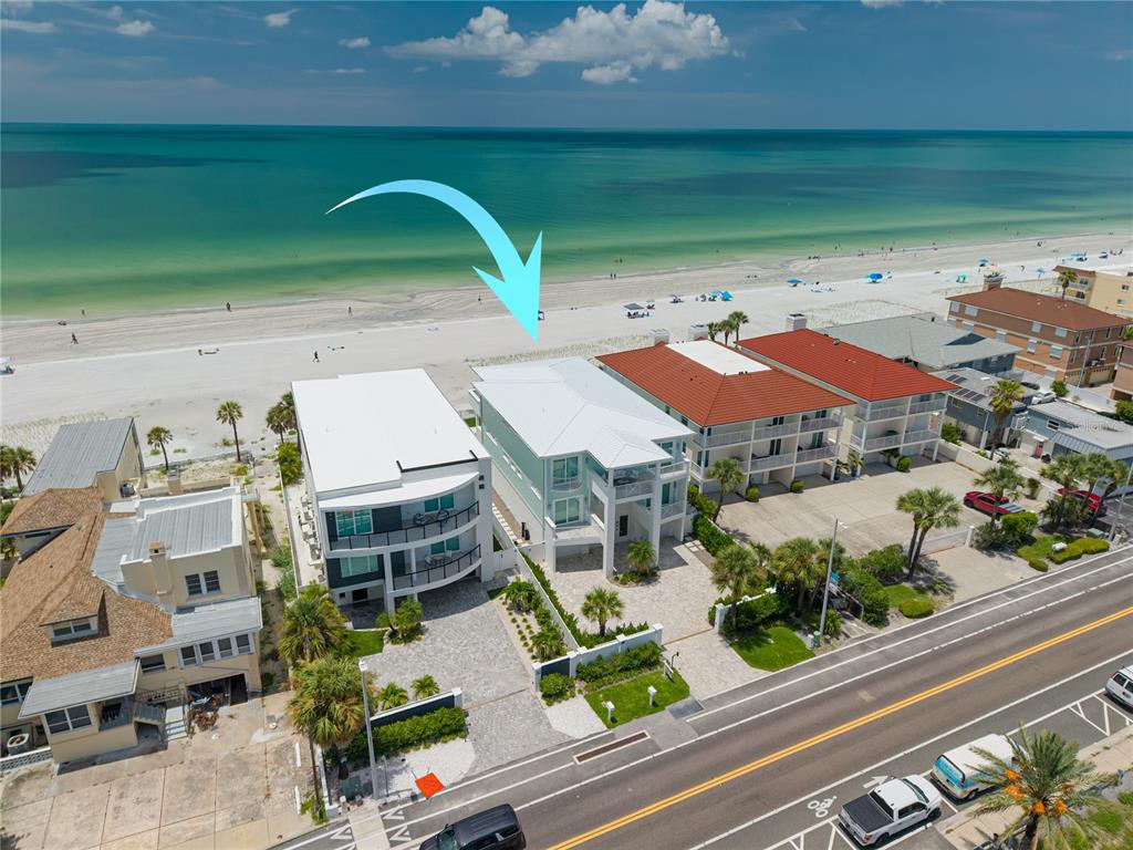 An aerial view shows a light green beach house with a white roof facing the ocean — 34 GULF BOULEVARD, INDIAN ROCKS BEACH, FL