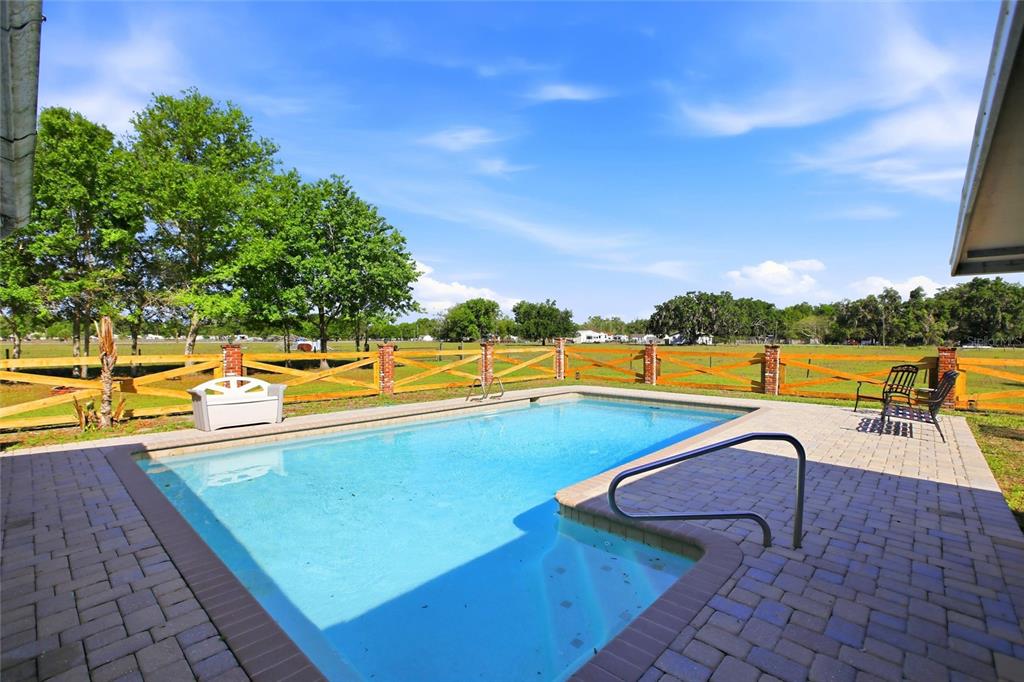 A rectangular swimming pool with a paved deck and wooden fence in a grassy yard — 3903 EDISON AVENUE, BOWLING GREEN, FL