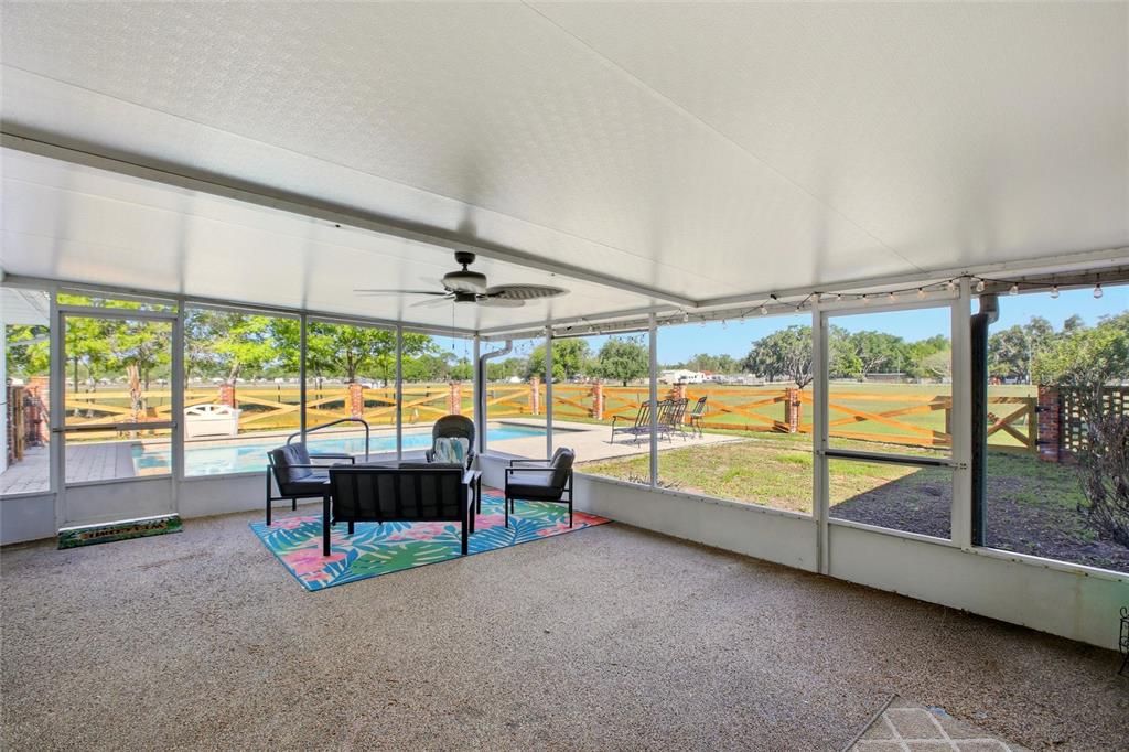 A screened-in patio features a concrete floor, outdoor furniture, and a view of a swimming pool — 3903 EDISON AVENUE, BOWLING GREEN, FL