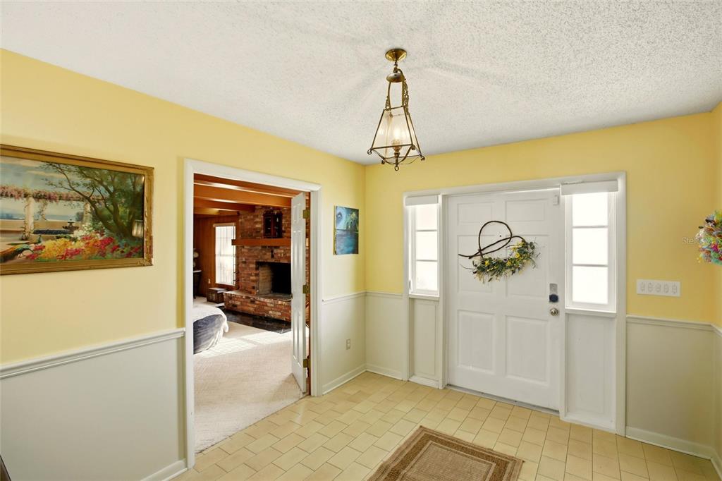 An entryway with yellow walls, white wainscoting, tile flooring, and a white front door — 3903 EDISON AVENUE, BOWLING GREEN, FL
