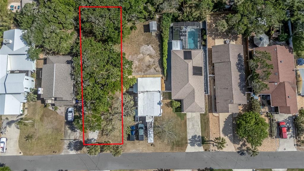 An aerial view shows a vacant, tree-covered residential lot outlined in red between two houses — E 12TH AVENUE, NEW SMYRNA BEACH, FL