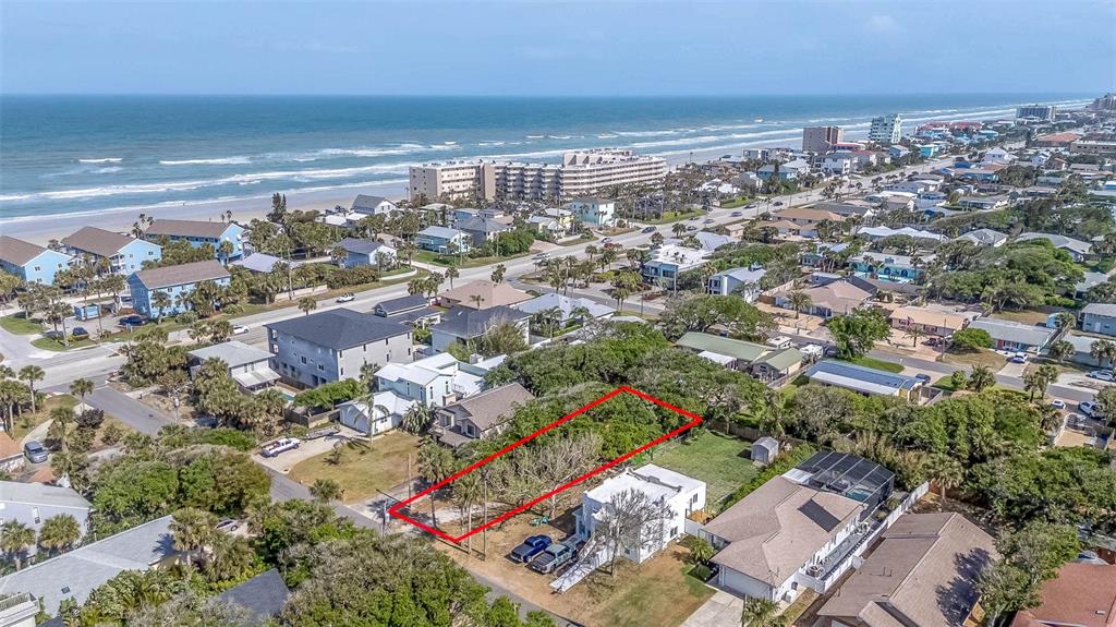 An aerial view shows a rectangular vacant lot outlined in red in a coastal neighborhood — E 12TH AVENUE, NEW SMYRNA BEACH, FL