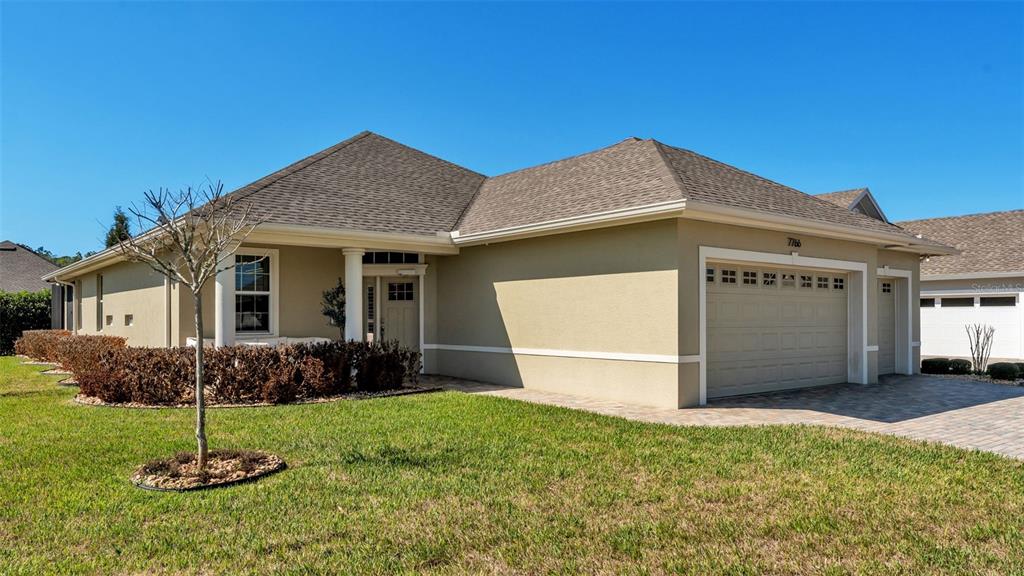 A tan single-story house with a two-car garage and a paved driveway — 7766 LAKE JAMES BOULEVARD, LAKELAND, FL