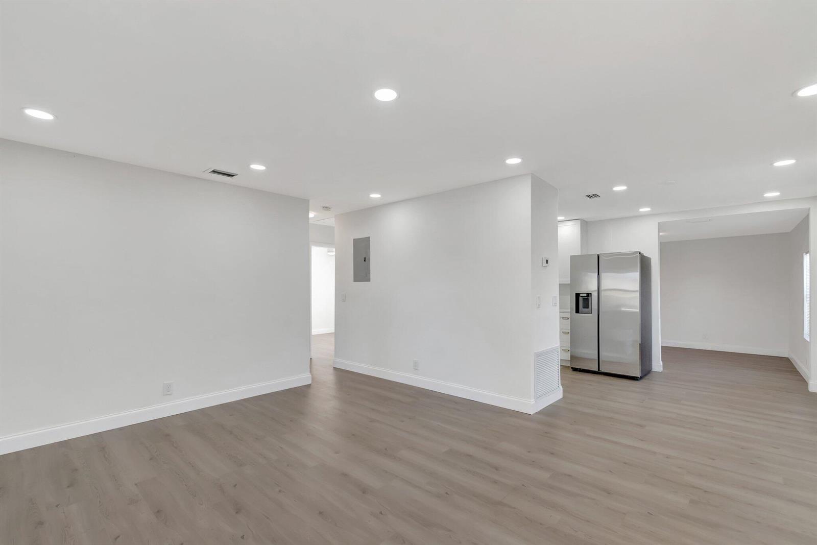 An open-concept living area features light gray walls, wood-look flooring, recessed lighting, and a refrigerator — 950 29th Street, West Palm Beach FL 33407, WEST PALM BEACH, FL