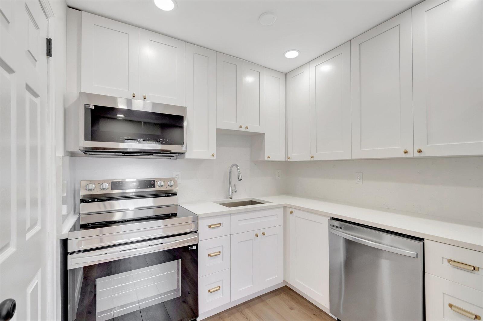 A modern kitchen features white shaker cabinets, stainless steel appliances, and light-colored countertops — 950 29th Street, West Palm Beach FL 33407, WEST PALM BEACH, FL
