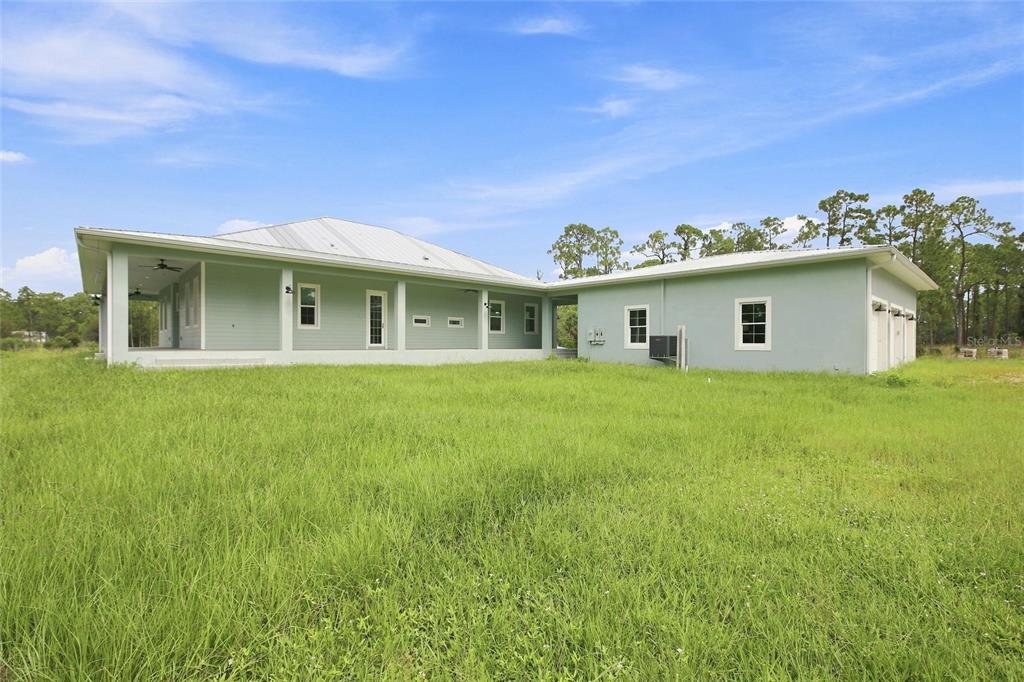 A light green, single-story house with a metal roof and a covered porch sits outdoors — 8146 TROPICAIRE BOULEVARD, NORTH PORT, FL
