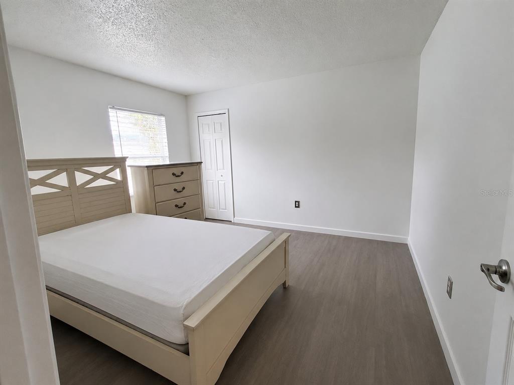 A bedroom features a light-colored bed frame, a matching dresser, and wood-look flooring — 449 HEATHER HILL BOULEVARD, DAVENPORT, FL