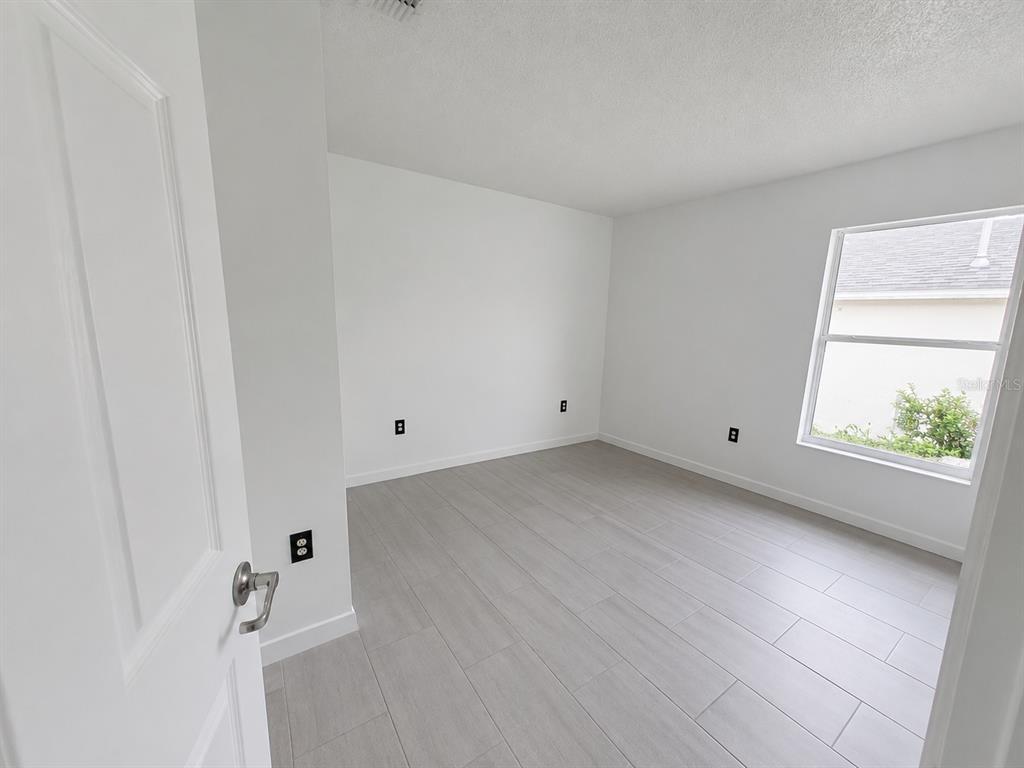 An empty room with white walls, light-colored tile flooring, and a single window — 449 HEATHER HILL BOULEVARD, DAVENPORT, FL