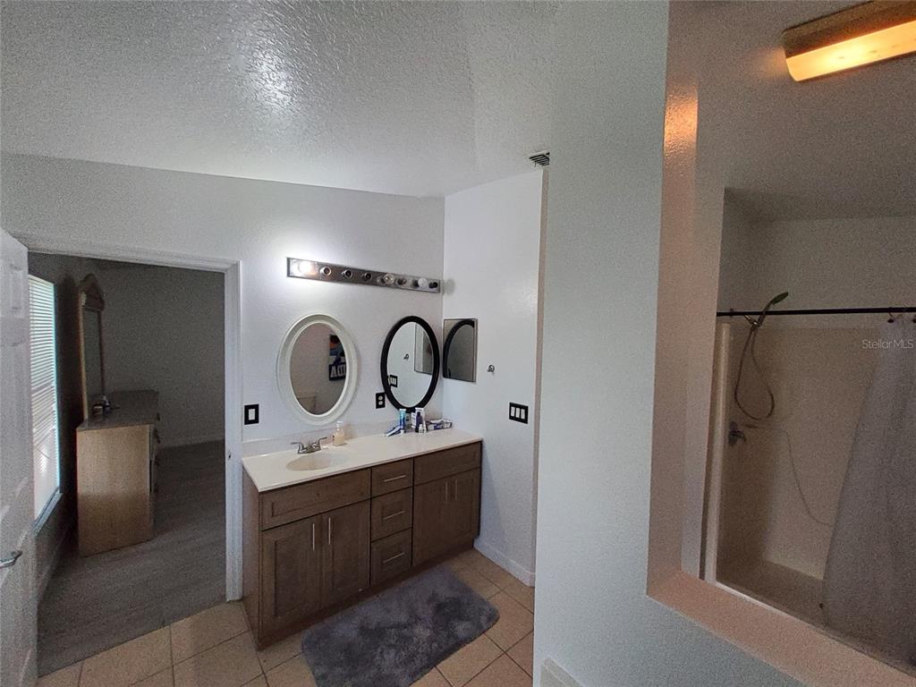 A bathroom features a vanity with two mirrors, a tiled floor, and a shower stall — 449 HEATHER HILL BOULEVARD, DAVENPORT, FL
