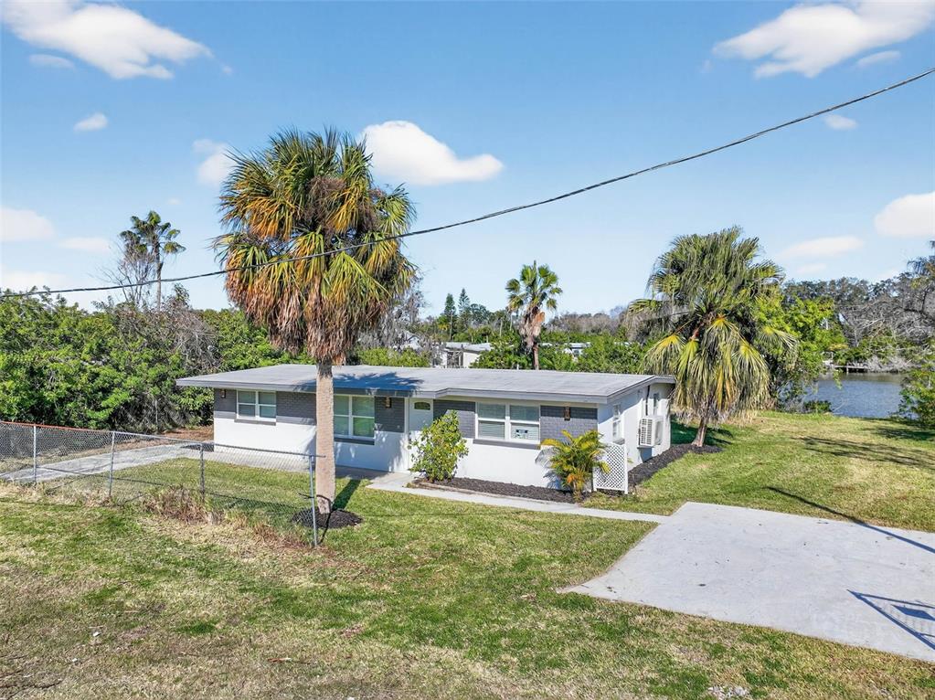 A single-story house with a gray roof and white exterior sits on a grassy lot — 4505 COTTONWOOD DRIVE, NEW PORT RICHEY, FL
