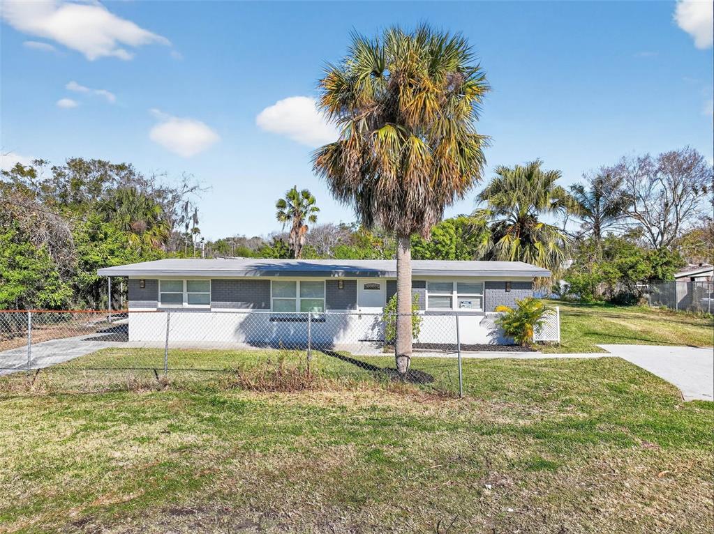 A single-story house with a gray and white exterior sits behind a chain-link fence — 4505 COTTONWOOD DRIVE, NEW PORT RICHEY, FL