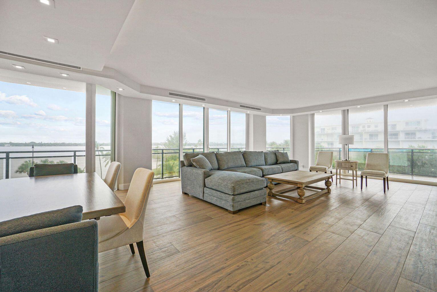 A spacious living and dining area with floor-to-ceiling windows, wood flooring, and water views — 3100 S Ocean Boulevard # 306n, Palm Beach FL 33480, PALM BEACH, FL