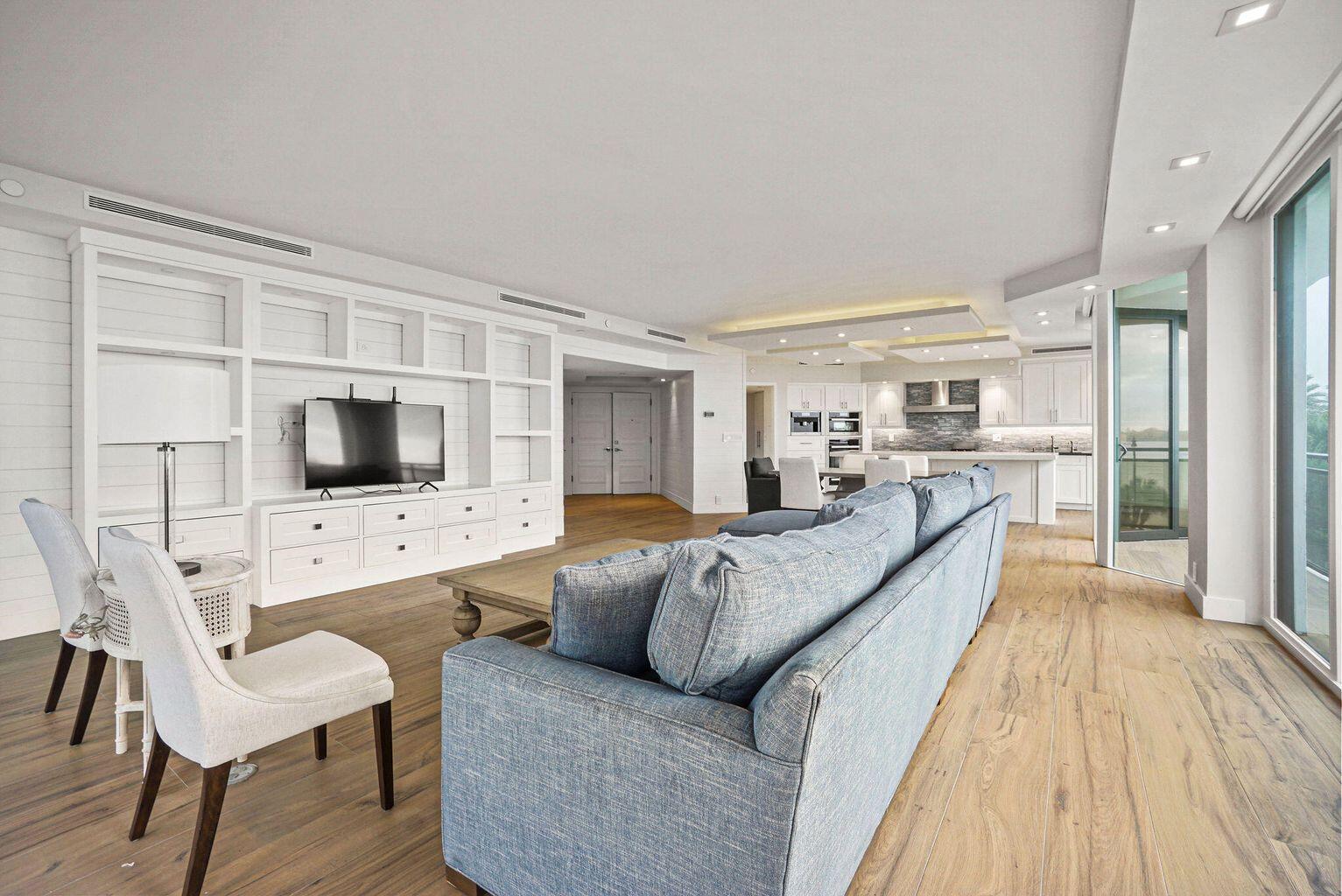 A living room with a blue sofa, white built-in shelving, and wood-look flooring — 3100 S Ocean Boulevard # 306n, Palm Beach FL 33480, PALM BEACH, FL