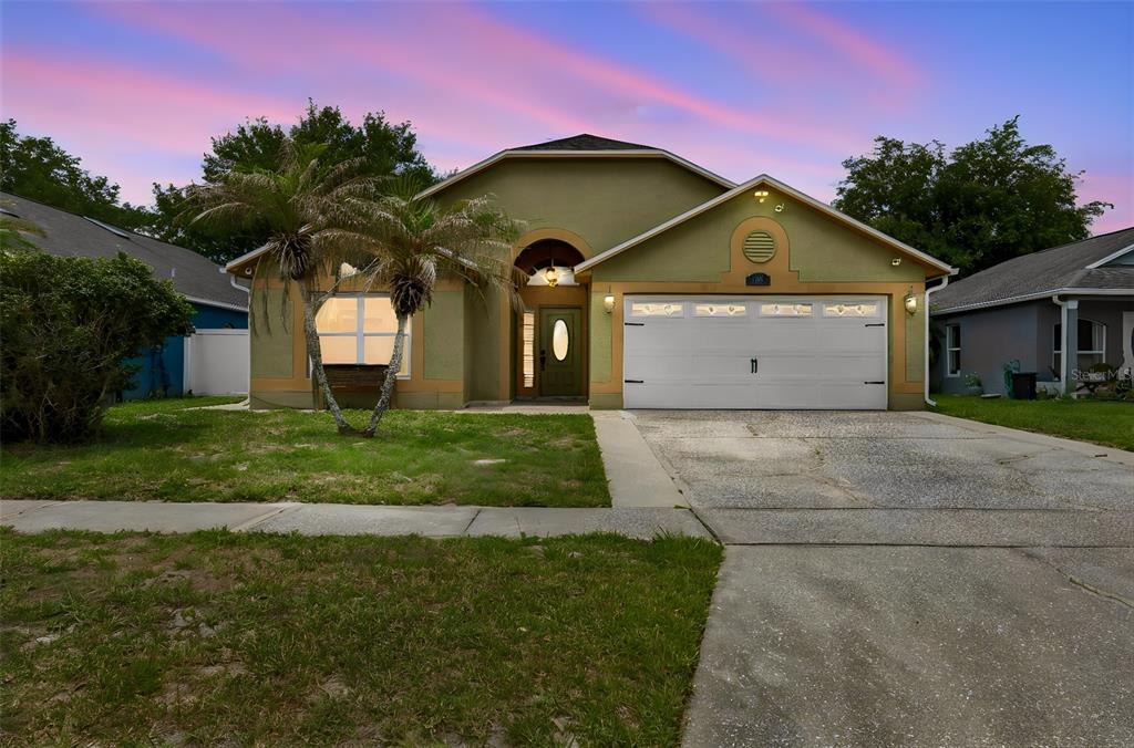 A single-story house with a green stucco exterior, a two-car garage, and a palm tree — 1008 OLD BARN ROAD, ORLANDO, FL