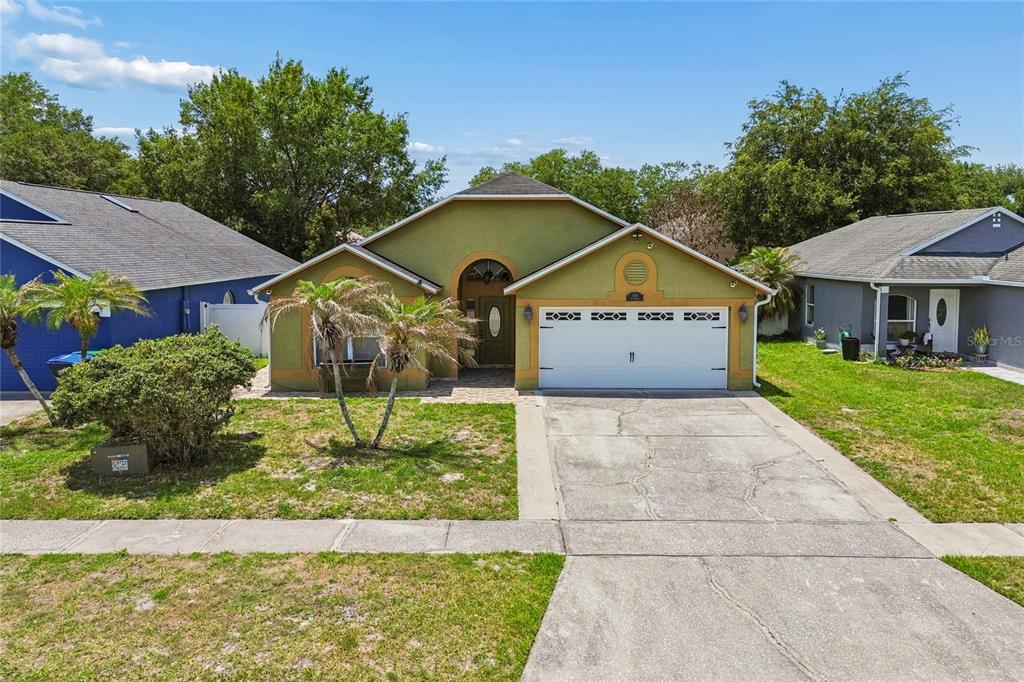 A single-story house with a green stucco exterior, a two-car garage, and a paved driveway — 1008 OLD BARN ROAD, ORLANDO, FL
